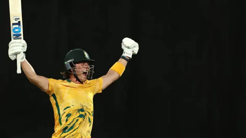 Dewald Brevis raises his arms after reaching a hundred